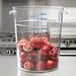 A Carlisle clear round polycarbonate food storage container full of apples.