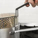 A hand holding a Vollrath Wear-Ever heavy duty aluminum fry pot with a handle.