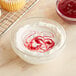 A bowl of whipped cream with red swirls on top of it.