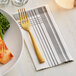 A Hoffmaster FashnPoint tissue dinner napkin with a fork on a plate with broccoli and fish.