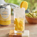 A bottle of DayPack Mango Sparkling Hop Water on a table with a glass of ice and a slice of mango in it.