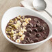 A bowl of Ghirardelli chocolate pudding with nuts and seeds.