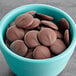 A blue bowl filled with Ghirardelli 100% Cacao Unsweetened Chocolate Liquor Wafers.