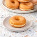A plate of Rich's glazed yeast donuts on a marbled surface.