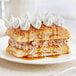 A white plate topped with Henry & Henry Puff Pastry Square pastries with whipped cream on top.