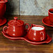 A red Fiesta sugar and creamer tray set on a red surface.