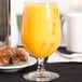 A Libbey Bristol Valley wine goblet filled with orange juice sits on a table next to croissants.