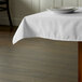 A white Intedge tablecloth on a table with a plate on it.