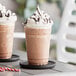 A close-up of two cups of chocolate milkshakes with whipped cream.