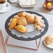 A plate of pastries on a table with a Hoffmaster Cambridge Lace doily underneath.