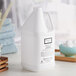 A white jug of Beekman 1802 Fresh Air Shampoo on a table.