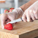 A person using a Schraf smooth edge paring knife to cut strawberries.