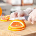 A person using a Schraf serrated edge paring knife to cut an orange.