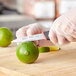 A person in gloves uses a Schraf serrated paring knife to cut a lime.