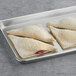 A tray of Orange Bakery sugared cherry turnovers on a gray surface.