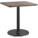 A Lancaster Table & Seating square table with a black metal base and reversible wooden top.