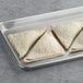 Three Orange Bakery sugared apple turnovers on a baking tray with white powder on them.