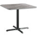 A Lancaster Table & Seating square table with a grey laminated top and black metal base.