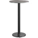 A round gray and white table top with a black pole base.