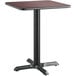 A Lancaster Table & Seating square table with a black base and a cherry top.