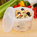 A translucent plastic deli container with pasta and olives in it with a translucent plastic lid.