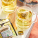 A glass mug of Twinings Budding Meadow Chamomile tea with a tea bag in it.