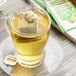 A glass cup of Twinings Energize Matcha, Cranberry & Lime Green Tea with a bag of tea in it.