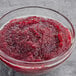A bowl of raspberry jam on a gray surface.