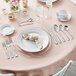 A table set with plates and silverware including Acopa Triumph stainless steel dinner knives.