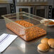 A Carlisle amber high heat plastic food pan filled with beans on a counter with bread.