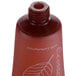 A close-up of a brown Ecossential Naturals conditioner bottle with a leaf on it.