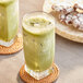A glass of Add A Scoop Premium Matcha Green Tea next to cookies.