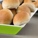 A green Keywest melamine bowl filled with rolls of bread.