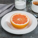 A half of a grapefruit in a Homer Laughlin bright white china bowl on a table in a breakfast diner.
