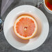 A half of a grapefruit on a Homer Laughlin Kensington Ameriwhite china bowl with a spoon and tea.