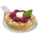 A spoon with a dessert on it with raspberries and cream in a round white display.