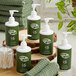 A group of green Noble Eco Novo Terra shampoo bottles with white caps on a table with green towels.