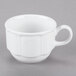 A Tuxton bright white china coffee cup with a handle on a gray surface.