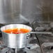 A Town aluminum sauce pan filled with red sauce on a stove.