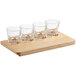 An Acopa wooden flight tray holding four espresso glasses.