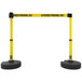 A yellow and black Banner Stakes barrier with tray.