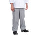 A person wearing a white chef coat and grey Chef Revival houndstooth pants.