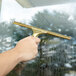 A hand holding a Unger brass window cleaner channel.