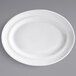 A close-up of a white Tuxton Concentrix oval platter with a curved edge.