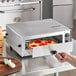 A pizza being cooked in a Carnival King stainless steel countertop oven.