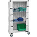 A Quantum white nylon cart cover on a white cart with shelves holding blue towels.