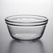 An Anchor Hocking clear glass bowl with a curved edge on a white surface.