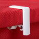 A white plastic Chef Master tablecloth clip on a red table.