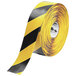 A roll of yellow and black tape with chevron patterns and a warning sign with Mighty Line label.