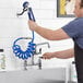 A man using a hose to wash a Waterloo pet grooming faucet.